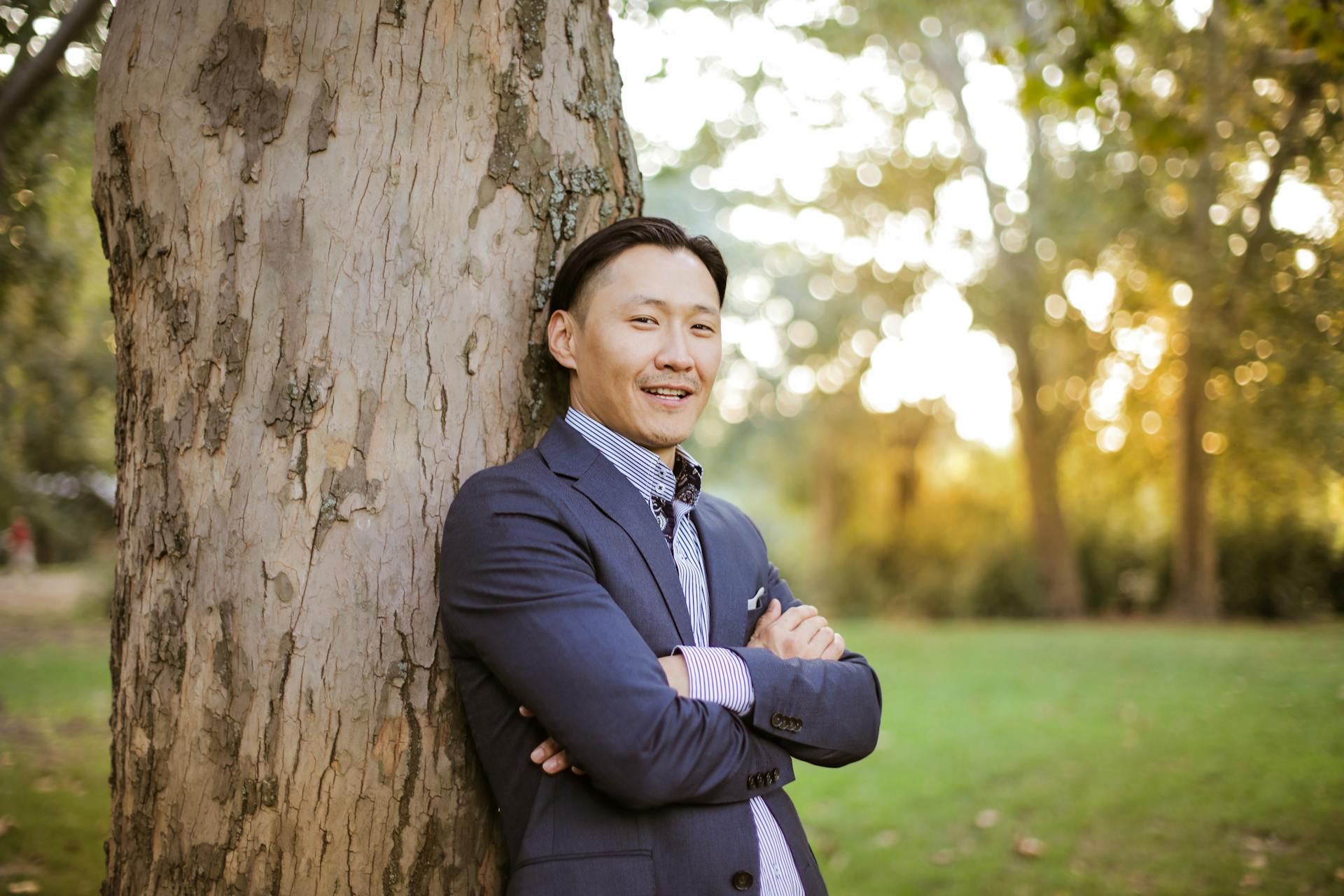 Happy man leaning against a tree in the park